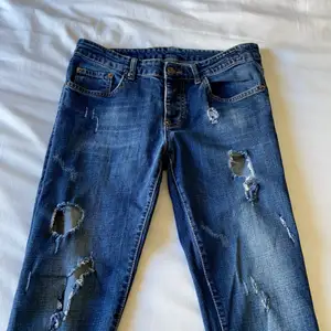 Mörkblå jeans med hål, de är fake Dsquared2. Det är storlek 42, men jag är 175cm lång och de passar mig i längden, de är dock tighta. De är knappt använd och så den är i bra skick. Jag bor i Norrköping och kan mötas upp, annars står köparen för frakten. Pris kan diskuteras!