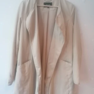 Beige jacka i knälängd  - Den har jacka är från Vila clothes Oanvänd,. XS storlek Jag hade beställt den för en månad sedan, men den kom i fel storlek och så jag lämnade inte tillbaka den.