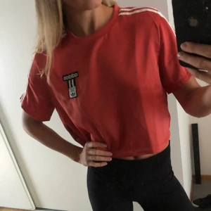 Croppad t-shirt - Croppad t-shirt från Adidas. Lite blankt material, fin kvalité. Orange-aktig färg. 