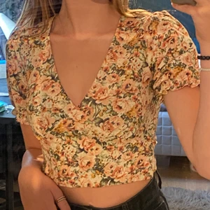 Blommig topp - En blommig v-ringad topp med puffärm från Gina tricot. Toppens armar är lite insydda så puffarna på armarna är inte lika stora. Använd 1 gång och i nyskick💗frakt står köparen för