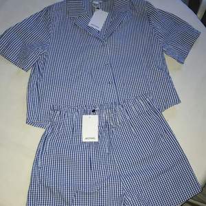 Detta är ett blå och vit rutigt det från Monki med både shorts och tröja/skjorta. Det är helt oanvänt och har lapparna kvar, säljer Pga att den är för stor. 