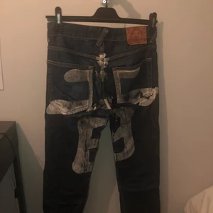 Evisu jeans - Jeansen är i mycket bra skick, dock har trycket där bak börjat slitas av lite då de är från runt 2006-2007. Själv anser jag att det ger byxorna karaktär. Storleken är 30x30 men passar även 20x30. Det japanska tecknet betyder ”bakom”. Billigaste evisujeansen på plick just nu!