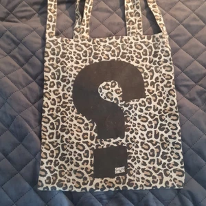 Tygpåse  - Leopardmönstrad tygpåse med ett frågetecken(?)på framsidan(ej på baksidan) har ETT långt axelband och TVÅ små band.