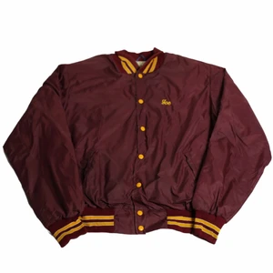 Joe - Vintage Varsity Jacka  - En riktigt Nice vinröd och orange varsityjacka/vindjacka/bomberjacka etc. som är gjord av nylon och därför perfekt för hösten då man vill skydda sig mot vind. Är från nittiotalet och från usa och därmed troligtvis använd av folk som gick på college. 