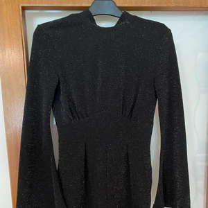 Svart glittrig byxdress - Glittrig byxdress med knytning där bak, utsvängda armar. Köparen står för frakten🌸