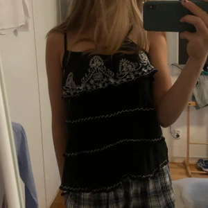 Linne med mönster - Säljer detta söta linne som är såå bekvämt💕banden är justerbara så det går att få kortare eller längre. Linnet består av 4 volanger som är broderade med vitt coolt mönster. Den är i storlek M men eftersom den är justerbar så går den att få kortare, jag är 169🧸💓