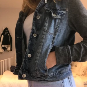 Jeansjacka - Jeansjacka med tyg ärmar och luva. Snygg och i bra skick. Jag använder den inte längre och har aldrig riktigt gjort det så den är i bra skick. 