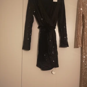 Svart paljett klänning - Svart fest paljett klänning med snöre i midjan stl 38 oanvänd med lapp kvar. 