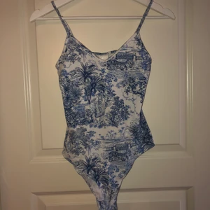 Super fin body stl xs - Jätte fin vit body med blå dekoration. Använd 2 gånger men har tyvärr blivit förliten för mig och kommer därmed inte till användning. 