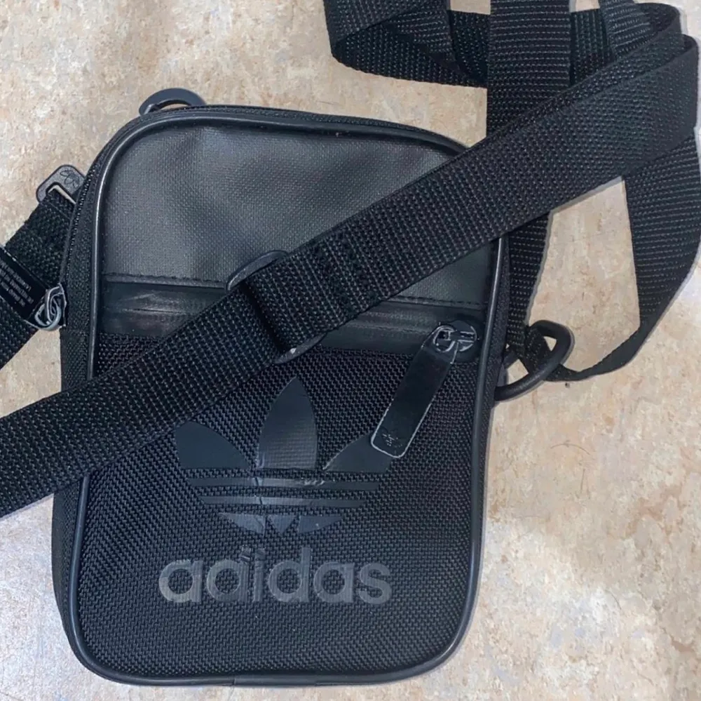 Säljer en svart Adidas Axel mini väska! Pris 100kr   Passar för att lägga små saker som pengar.  Färgen har lite försvunnit bort ❗️❗️  Som ni ser på bilden   Skriv vid intresse!💞. Accessoarer.