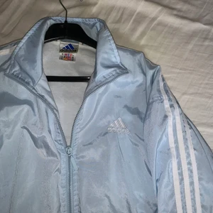 Adidas vintage vindjacka - Jättefin felfri ljusblå vintage adidas vindjacka! Står storlek 160 i den men skulle säga att den är en M