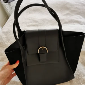 Handväska - Handväska med gulddetalj köpt på Åhléns. Jättefin modell och bra storlek. Helt oanvänd. 