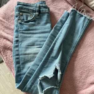 Jeans - Blå lågmidjade jeans från Lager 157 i storlek S. Hål på båda knäna & avklippta vid fötterna. Superfin ljusblå färg nu till våren/sommaren.