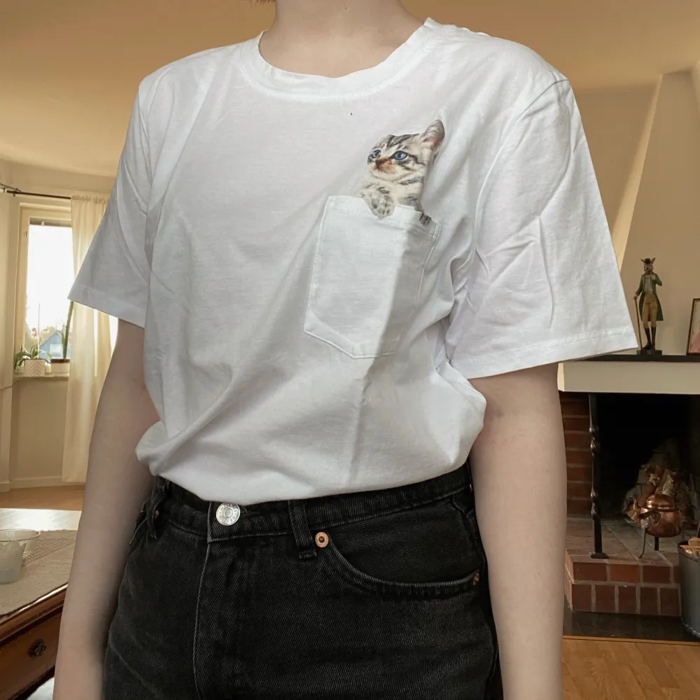 En söt t-shirt från H&M med en katt i bröstfickan! Frakt 45 kr 🌿 Finns i Västerås och tillfälligt Malung. . T-shirts.