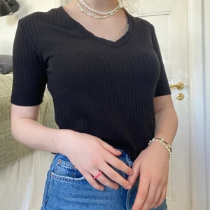 Ribbad t-shirt  - En lite roligare variant av din vanliga basic svarta t-shirt! Denna har en lite djupare v-ringning, en något längre ärm och är ribbad. Den är i bra kvalitet med ett tjockare material och därmed inte alls genomskinlig! 