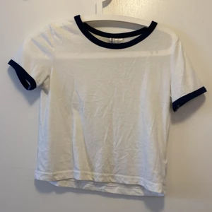 Tshirt - En basic T-shirt med mörkblåa detaljer. Använd och är lite nopprig men det syns inte! Därav priset.