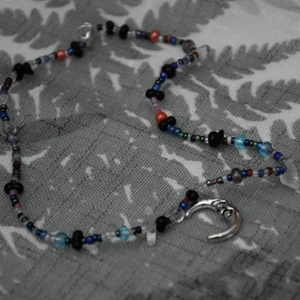 Pärlhalsband måne - Flerfärgat pärlhalsband åt det blåa hållet med en silvrig månberlock. 