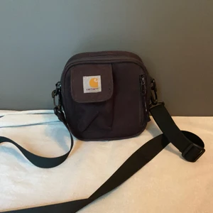 Carharttväska - Trogen väska som är mycket rymlig! Får plats två burkar öl. Väl använd. 3 fickor plus ett ytterfack. Älskar den här väskan!! Kardborrebandet fungerar ej långre på ytterfacket men jag har haft minn busskort där utan att ha tappat bort busskortet 