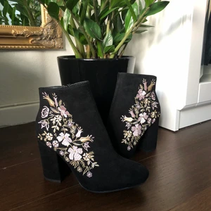 Svarta Boots Med Broderidetalj - Unika boots i nyskick (använda 1 gång) beställda från JustFab. Utsida av mockaimmitation med broderade blommor. Säljer då de inte kommer till användning. Kan mötas i Uppsala eller skicka (frakt tillkommer, godkänner SafePay).