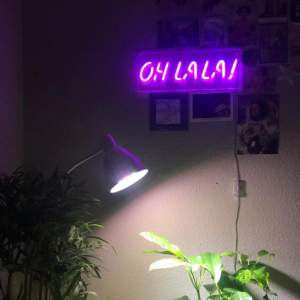 En neonlampa/neonskylt som det står ”Oh La La!” på. Ger ett lila ljus i hela rummet när det är mörkt. 40cm lång och 15cm hög. Sätts upp på väggen med två skruvar i de översta hörnen. 
