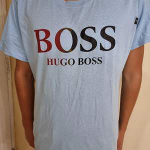 Oanvänd Hugo Boss t-shirt med centrerad text och ljusblå bakgrund. Simpel design funkar med det mästa. Framhäver dina armar och är väldigt behaglig att ha på sig.       (!Tar häldst swish!)
