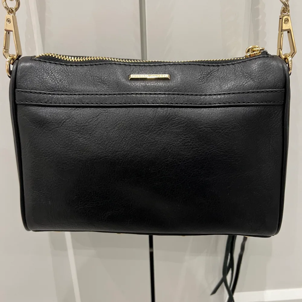 Helt ny väska från Rebecca Minkoff i otroligt fint skick, nyskick. En väska i svart läder med guldiga detaljer. Dustbag följer med. Betalning sker via swish och köparen står för frakten. . Väskor.