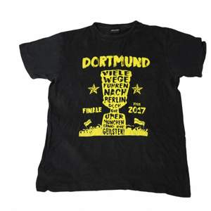 En cool graphic t-shirt med gult tryck från fotbollsklubben Dortmund. Köpt från en retro butik i Stockholm. Perfekt för en tidig 00s typ av stil. 