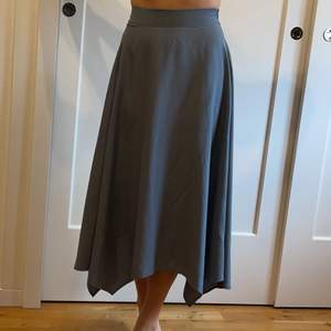 Asymmetrisk kjol med slät midja och resor i ryggen, dragkedja i sidan. Priset excl frakten 