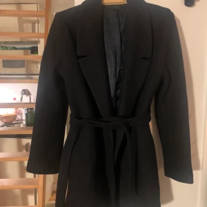 Cos ull kappa  - En Cos kappa av ullblandning. Är en mörkmörk blå färg men kan se svart ut. Kommer med bälte. Storlek 42 men passar som oversize kappa också 