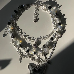 Asymmetrical butterfly necklace  - Jätte fint handgjort silvrigt halsband med några svarta, gråa och genomskinliga pärlor. Halsbandet har en lagom stor grå fjäril. Halsbandet är också justerbart<3