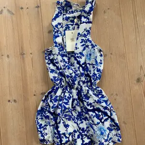 Blå blommig playsuit från WINONA! Kommer med tillhörande snörning. Snygg urringning framtill. Stl S