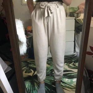 Beiga ”linne” byxor  - Ett par beiga ”linne” typ av byxor med band som knyts vid midjan! Fina och säljs endast för att de inte kommer till andvändning längre, har ett litet litet hål vid knapparna som inte syns eller märks alls (bild 3)! Köparen står för frakten:) 