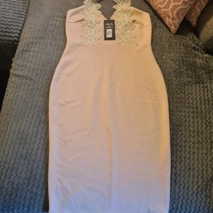 AX paris  - Säljer en helt ny  finklänning från märket AX PARIS i storlek 12 motsvarar M-L i svensk storlek. Klänningen knäpper du i ryggen och färgen är rosa med vit spets som man knäpper runt halsen. Nypris 1500 säljer den för 900 men priset går att diskutera. Skickas med spårbart paket 