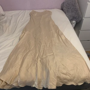 Glimrande cremefärgad klänning - ✨En vacker glimrande cremefärgad klänning. Den är lång och slutar lite ovanför mina fotknölar. Den är mycket fin men aldrig använd sen jag köpte den second hand. Det står att den är från märket Bla-Bla i strl M✨