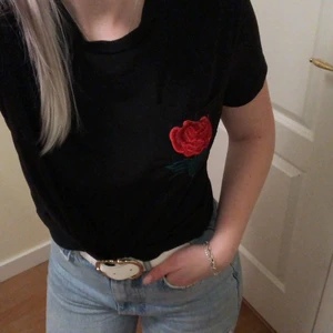 Ros T-shirt  - Simpel svart T-shirt med en ros på vänstra bröstet, storlek 36/s