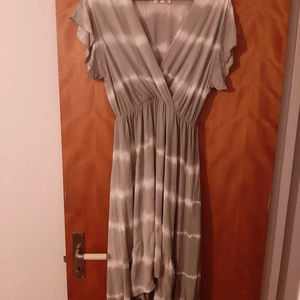 Klänning - Superfin klänning inköpt i somras strl L på butiken alternativet. Står ej märke mer än made in italy. Ner till fötterna baktill och strax ovan knäna framtill. Endast testad men aldrig använd då jag tyvärr inte tycker jag passar i denna typ av klänning.  Ljusgrön/vit (kan se något grå ut på bild) 100% viskos.  