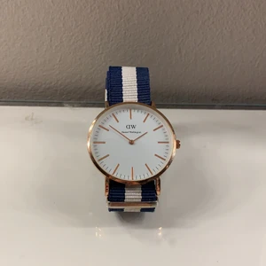 Daniel Wellington klocka - Super fin Daniel Wellington klocka blå/vit superbra skick, bandet är avklippt men vid det 8onde hålet så jag som har en ”normal stor handled” har på innersta hålet🥰      Detta är ett väldigt billigt pris för en så fin klocka som det ändå är☺️.  köparen står för frakten som till kommer (66kr).  Nypris: 1400kr