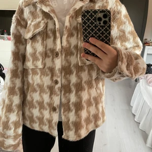 Rutig jacka  - Hundtandsmönstrad jacka i beige/vit i storlek 34, men sitter ganska avslappnat. Köpt för 800kr från NAKD. Frakt kostar 66kr. 
