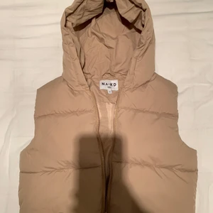 NAKD puffväst - Helt ny beige croppad puffervest från NAKD, storlek S. Köpte för några veckor sedan men har aldrig kommit till användning, därav inga bilder med den på. Modellen på bilden har på sig strl S. Nypris 549:-. Köparen står för frakten! 