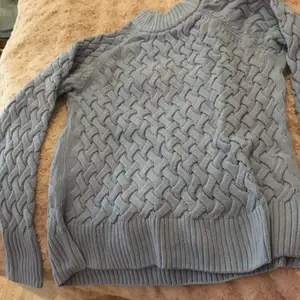 Blå (ser grå ut på bilden) stickad långärmad tröja med flätmönster från Cubud i strl M.
