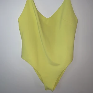 Gul body från H&M strl L - Gul body från H&M i storlek L. Den har knäppen mellan ben. Aningen djup i rygg. Helt oanvänd bara testad, prislappen kvar. Den är stretchig i tyget och skön mot kroppen.