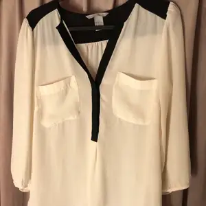 En skjorta i färgerna svart och vit från H&M, aldrig använd så är i det bästa skicket. Armarna på skjortan slutar under armbågarna när den sitter på. 