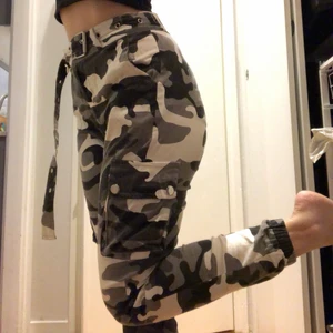 Coola kamouflagebrallor - Dessa är köpta på Shein så de är stretchiga och rätt tunna i tyget. Passformen är dock riktigt bra! Kamouflagemönstret består av svart, grått och vitt. Benen är snörpta med resår vid anklarna. Skärpet är långt och insytt. Katt finns i hemmet!