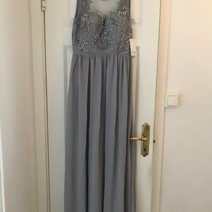 Sån vacker klänning med dekorativ framdel - Oanvänd klänning. Strl 36. Grå i färgen. Märket är Chiara Forthi Milano
