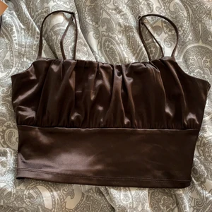 Topp från Hm - Skit snygg silketopp från hm i en mörkbrun färg. Helt oanvänd med lappen kvar. I storlek S, men banden är reglerbara så passar xs men även M skulle jag säga. Skriv för mer info😊 