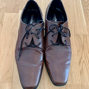 Herr skor i läder från Calvin Klein - Herr skor i skinn från Calvin Klein, storlek 45 (eller 11m),  passar bra till kostym eller jeans, använt enstaka gånger. fint skick.  Hämtas vid Kungsholmen eller Globen. Alt skickas mot porto. 
