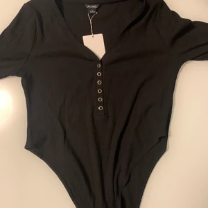 Svart body - Oanvänd långärmad body från Monki. Prislappen är till och med kvar. Ordinarie pris är 200. Kan mötas om man bor i Sthlm annars står man själv för frakten 