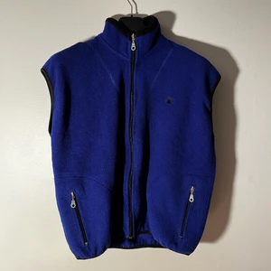 Blå Champion Fleece-Väst  - Blå Champion Fleece-Väst i fint skick, dock kan man hitta några små knottror lite här och där. Storleken går inte att se då etiketter missfärgats men skulle uppskatta en M/L för män. Midjebredden över fickorna när den ligger platt är 58cm. Fraktas spårbart med postnord, kan skickad med andra företag vid förfrågan.