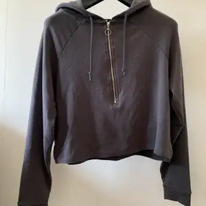 En väldigt fin grå croppad hoodie med luva och en halvdragkedja som ger hoodien en fin detalj