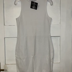 VIT KLÄNNING STL M - Vit klänning med halter neck i storlek M. Aldrig använd med prislappen kvar. Budgivning startar på 60 kr i komentarsfältet köp direkt för 100 kr 